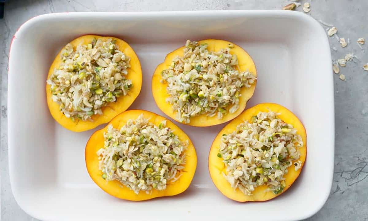 4 cut mango halves with topping, in a white rectangle dish.