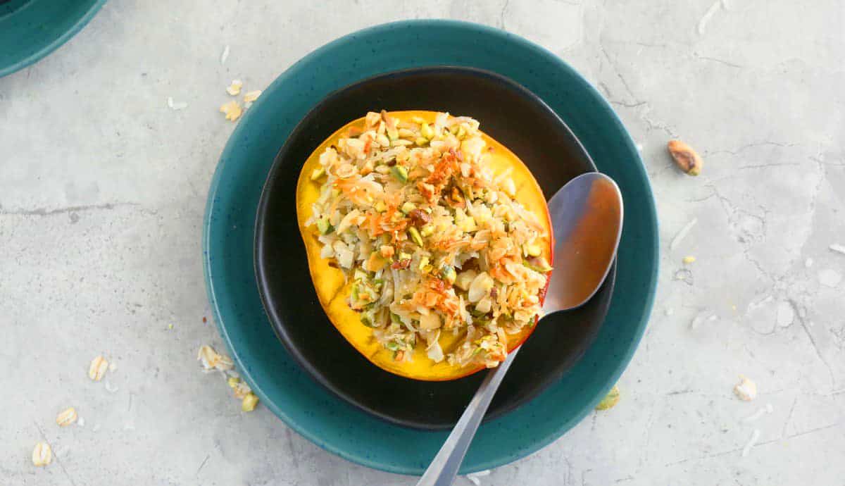 one baked mango half on green plate and a spoon on the side.