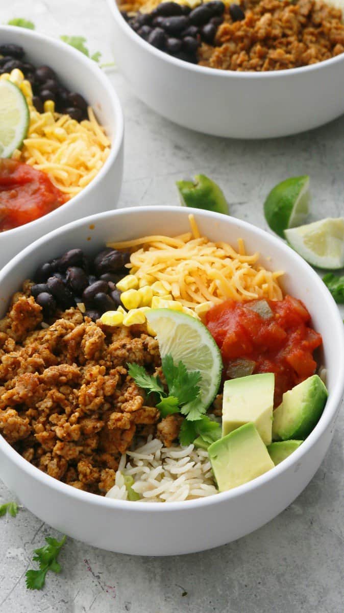 bowls with cilantro lime rice, mexican chicken, black beans and toppings.