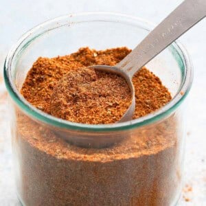 chicken taco seasoning in a glass jar along with a spoon.