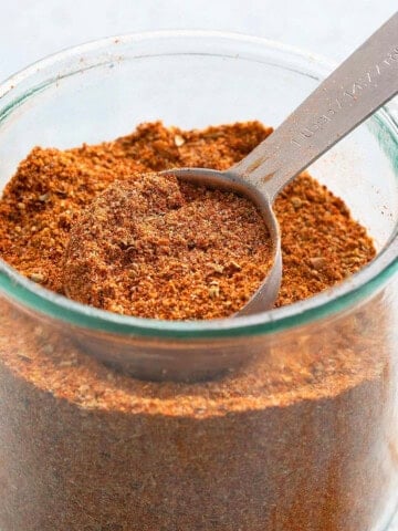 chicken taco seasoning in a glass jar along with a spoon.