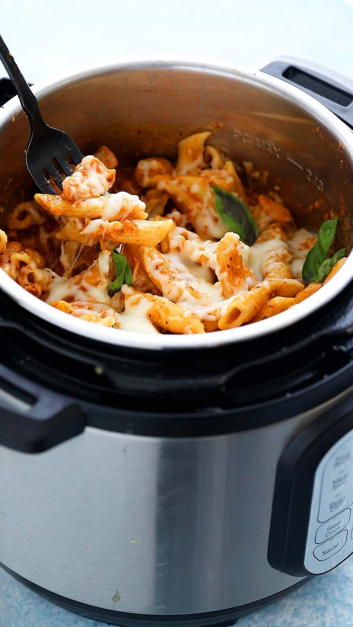 an instant pot filled with cooked pasta topped with cheese and basil. 