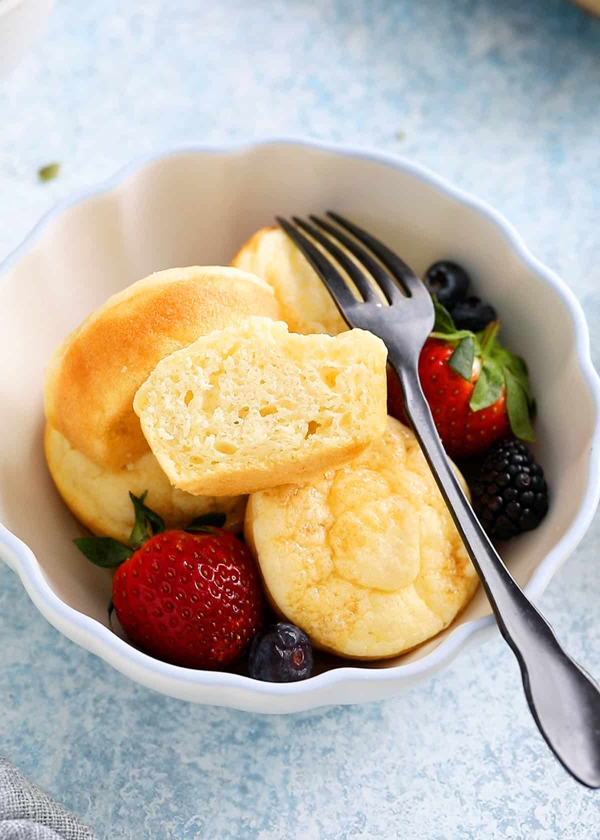 one white bowl with 4 baked pancake cups along with a black fork.