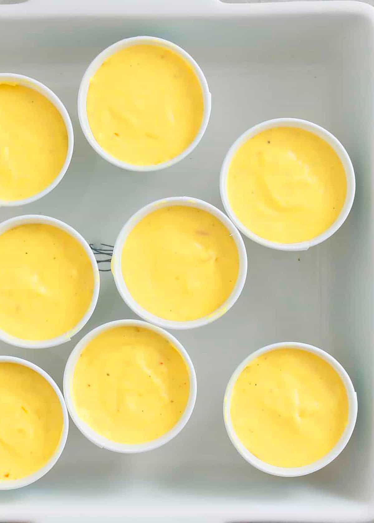 9 paper cups with yellow mango ice cream.