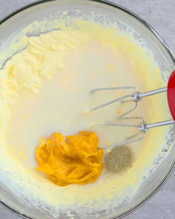 one glass bowl with yellow cream and a mixer.