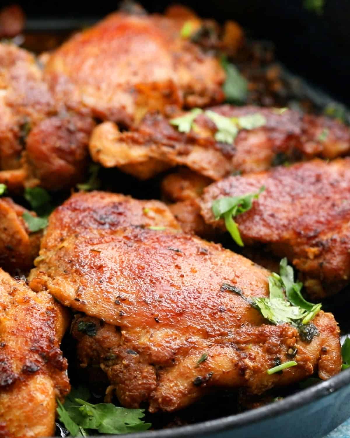 cooked brown chicken thighs placed in a black skillet.