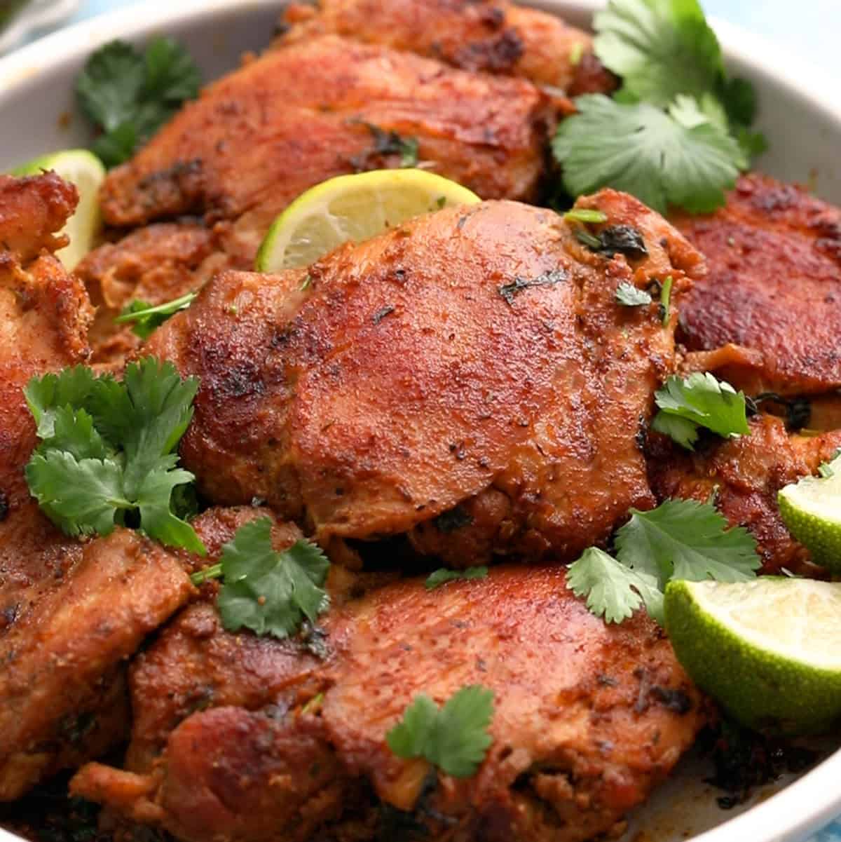 cooked brown chicken thighs placed in a round plate.