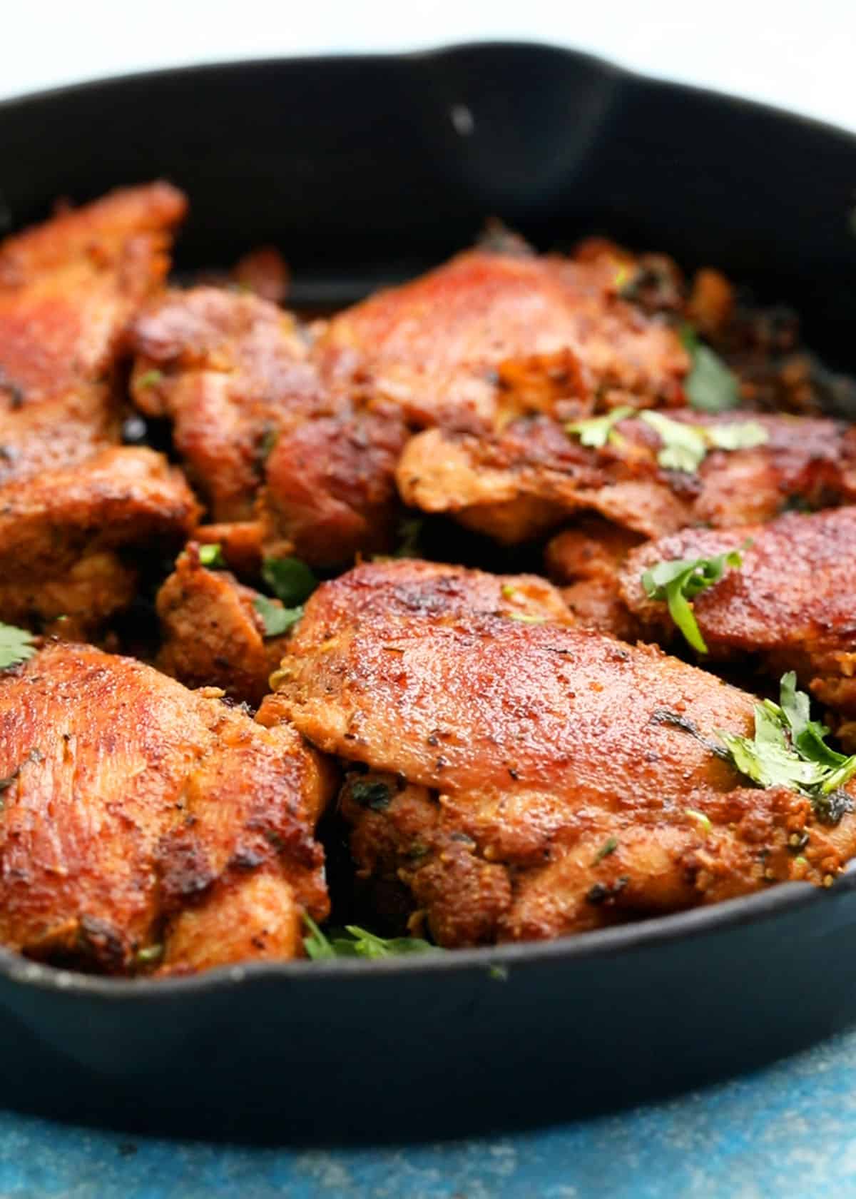 cooked brown chicken thighs placed in a black skillet.