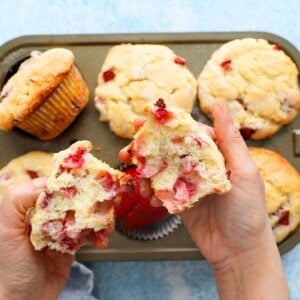two hands holding two halves of a strawberry muffin.
