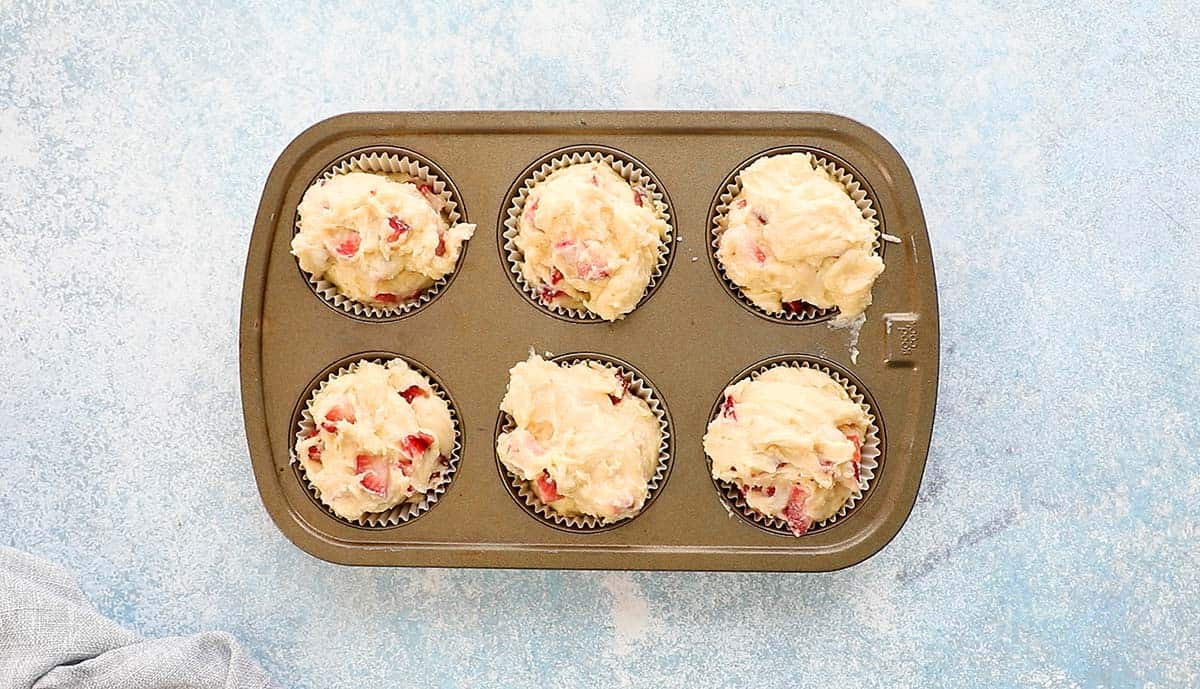 a 6 cup muffin pan filled with strawberry muffin batter.
