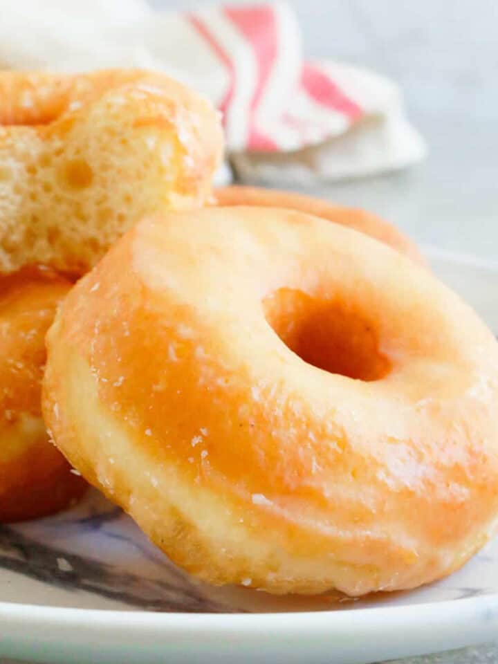 3 glazed donuts on a white plate.