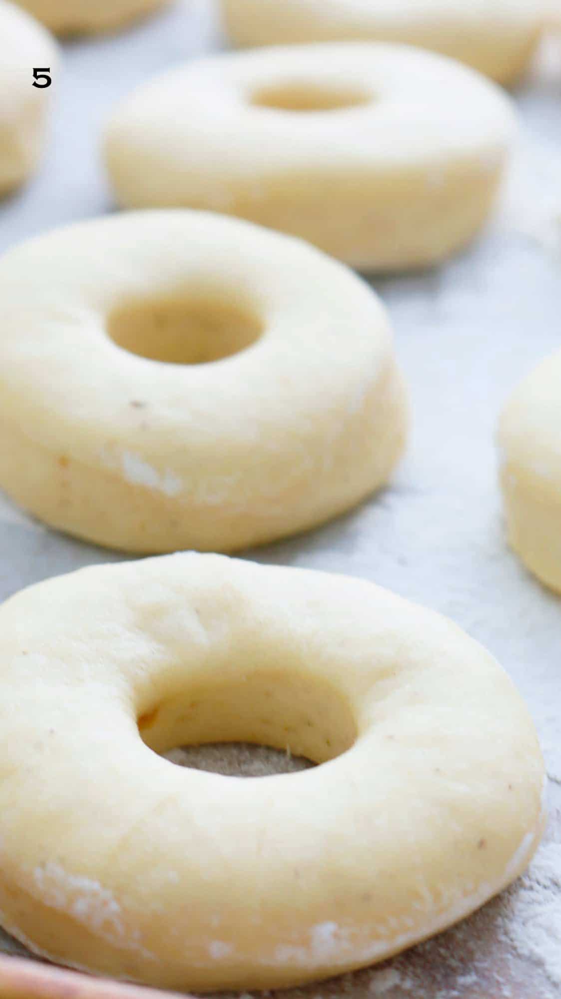 risen cut donut dough on parchment paper.