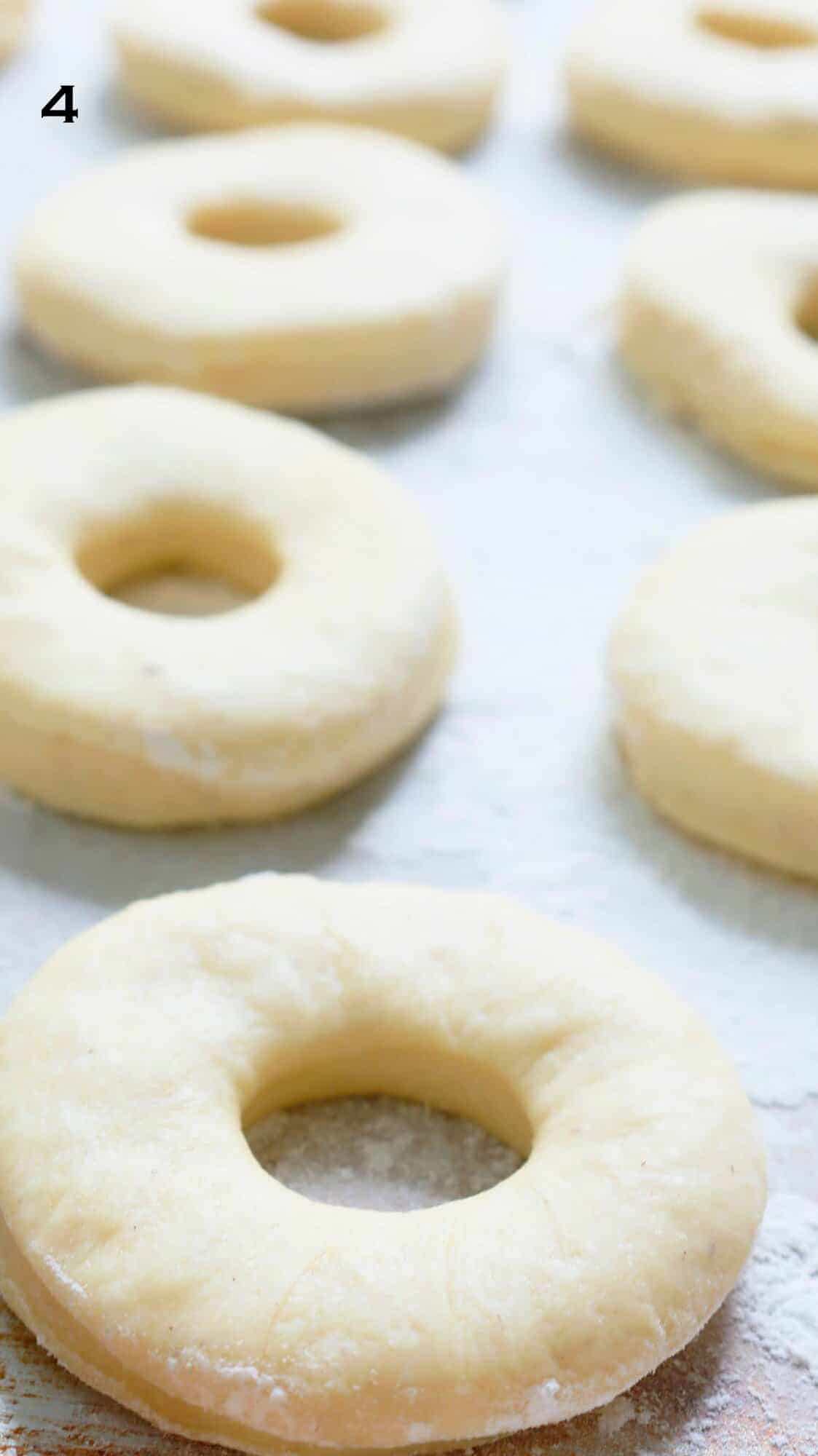 risen cut donut dough on parchment paper.