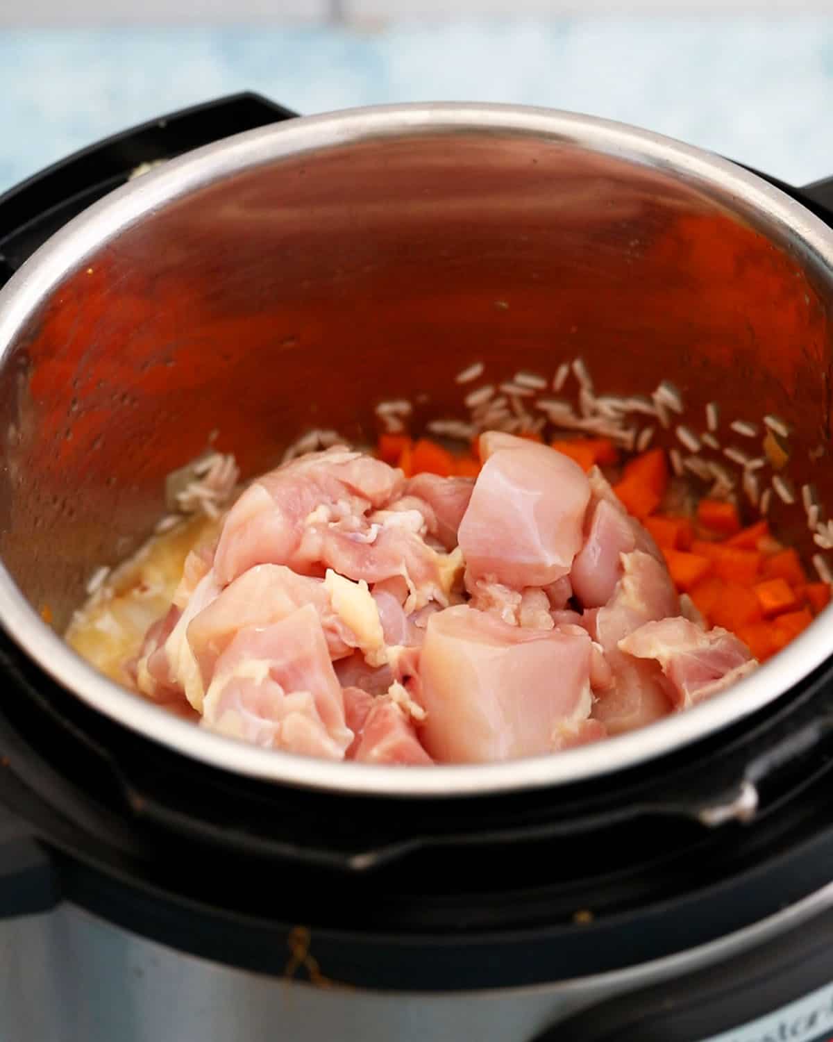 pink chicken pieces and rice cooking in an instant pot.