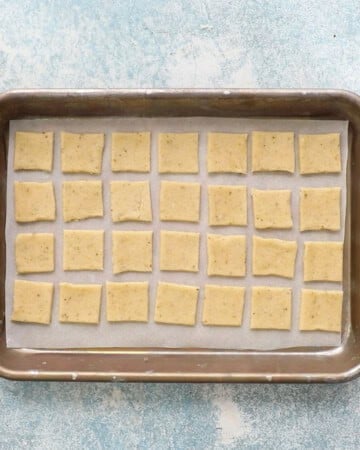 cut square shaped crackers placed in  a metal baking sheet.