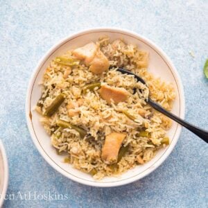 one white bowl with chicken and rice along with a black fork.