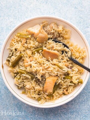 one white bowl with chicken and rice along with a black fork.