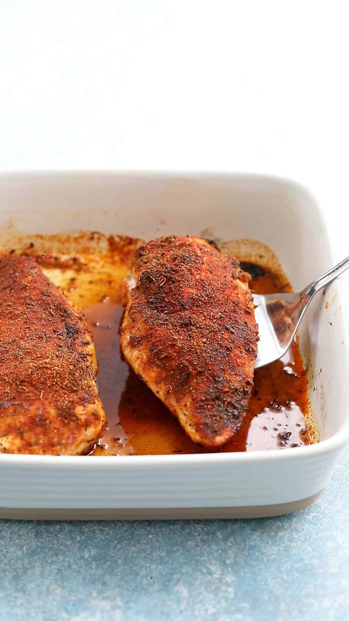 2 cooked chicken breasts on a white ceramic baking dish.