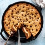 baked chocolate chip cookie in a black skillet along with two forks.