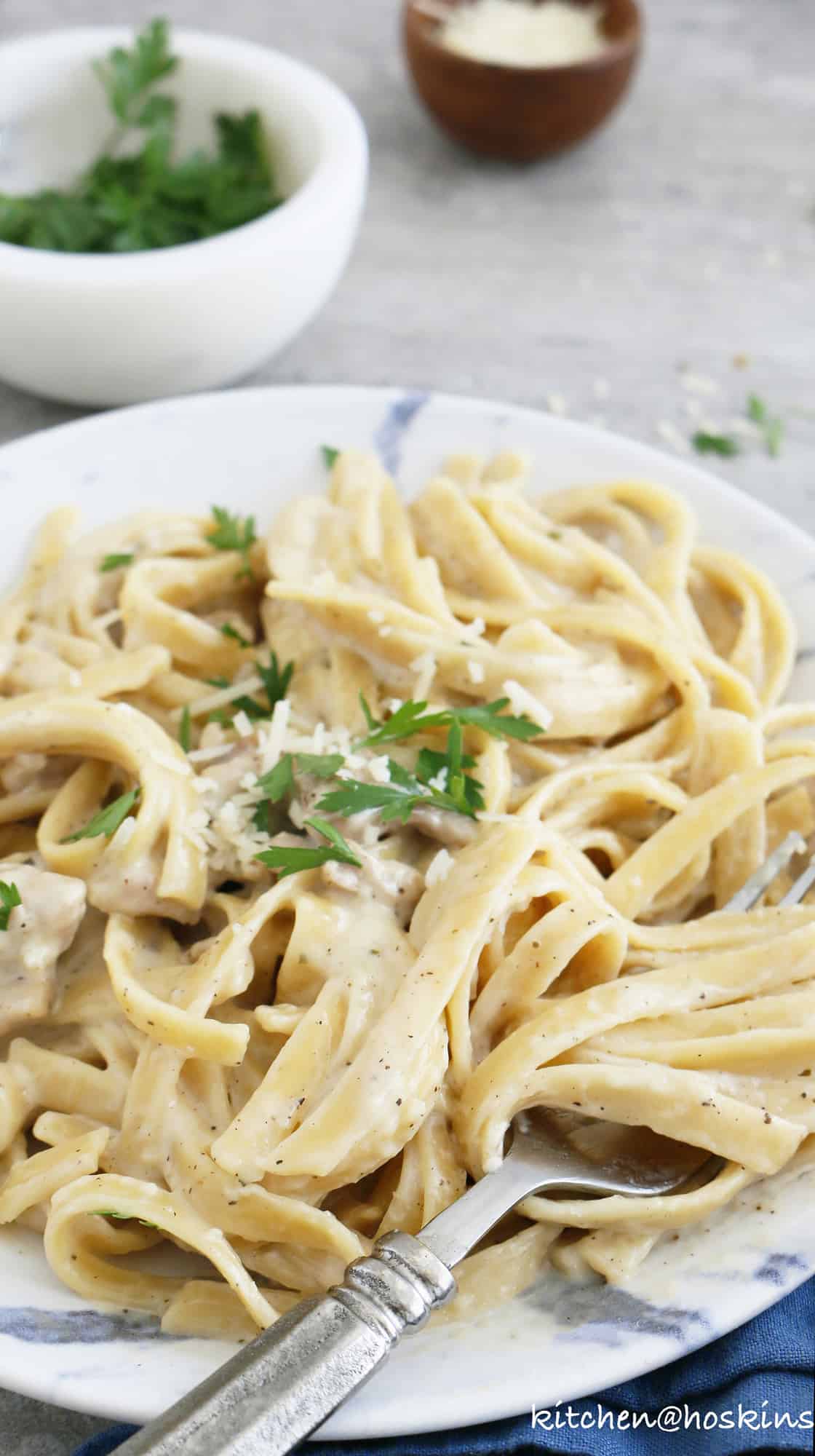 A side view of instant pot chicken alfredo on a blue plate
