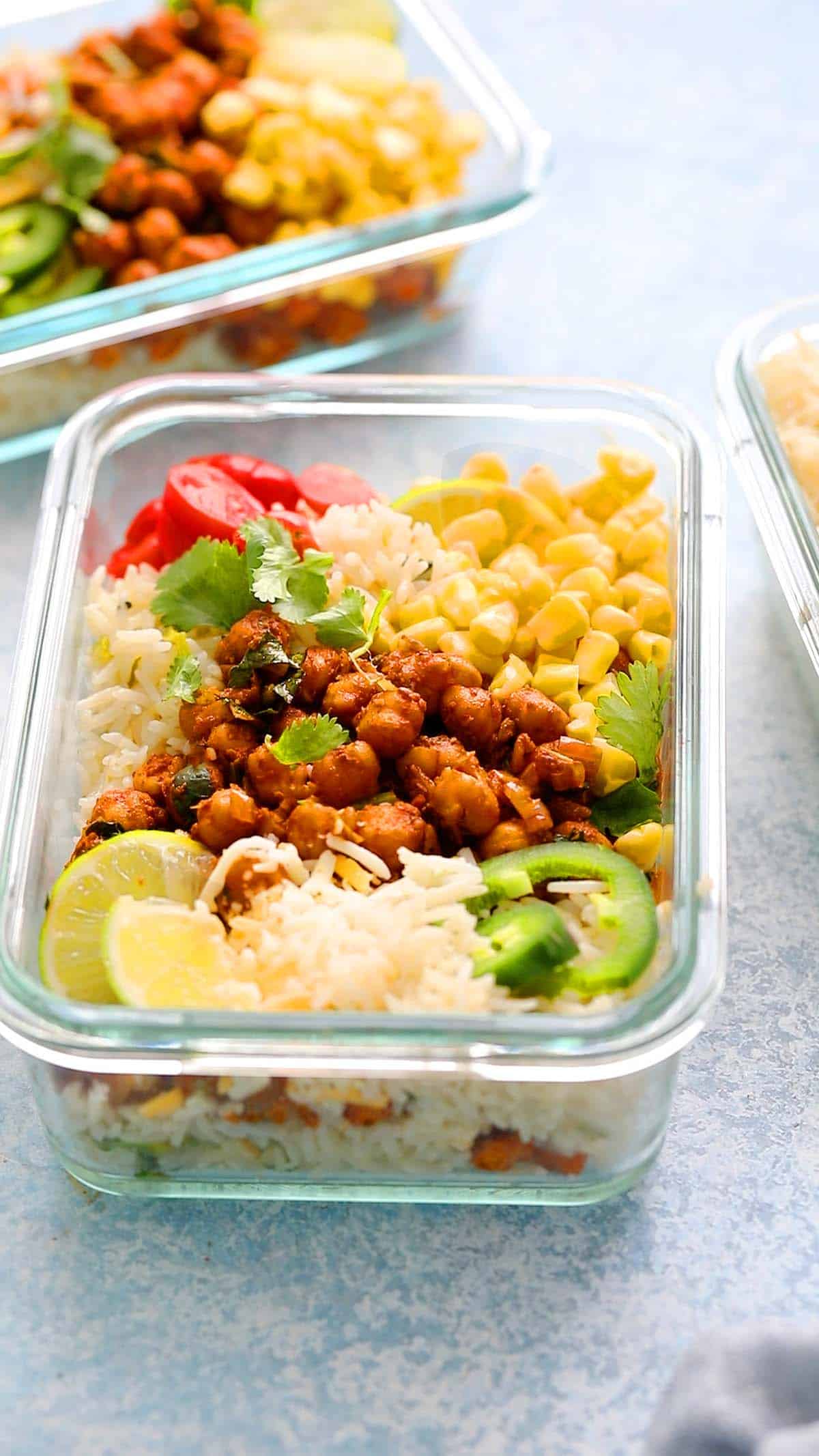 three rectangle glass bowls with cooked rice, chickpeas and all burrito bowl toppings.