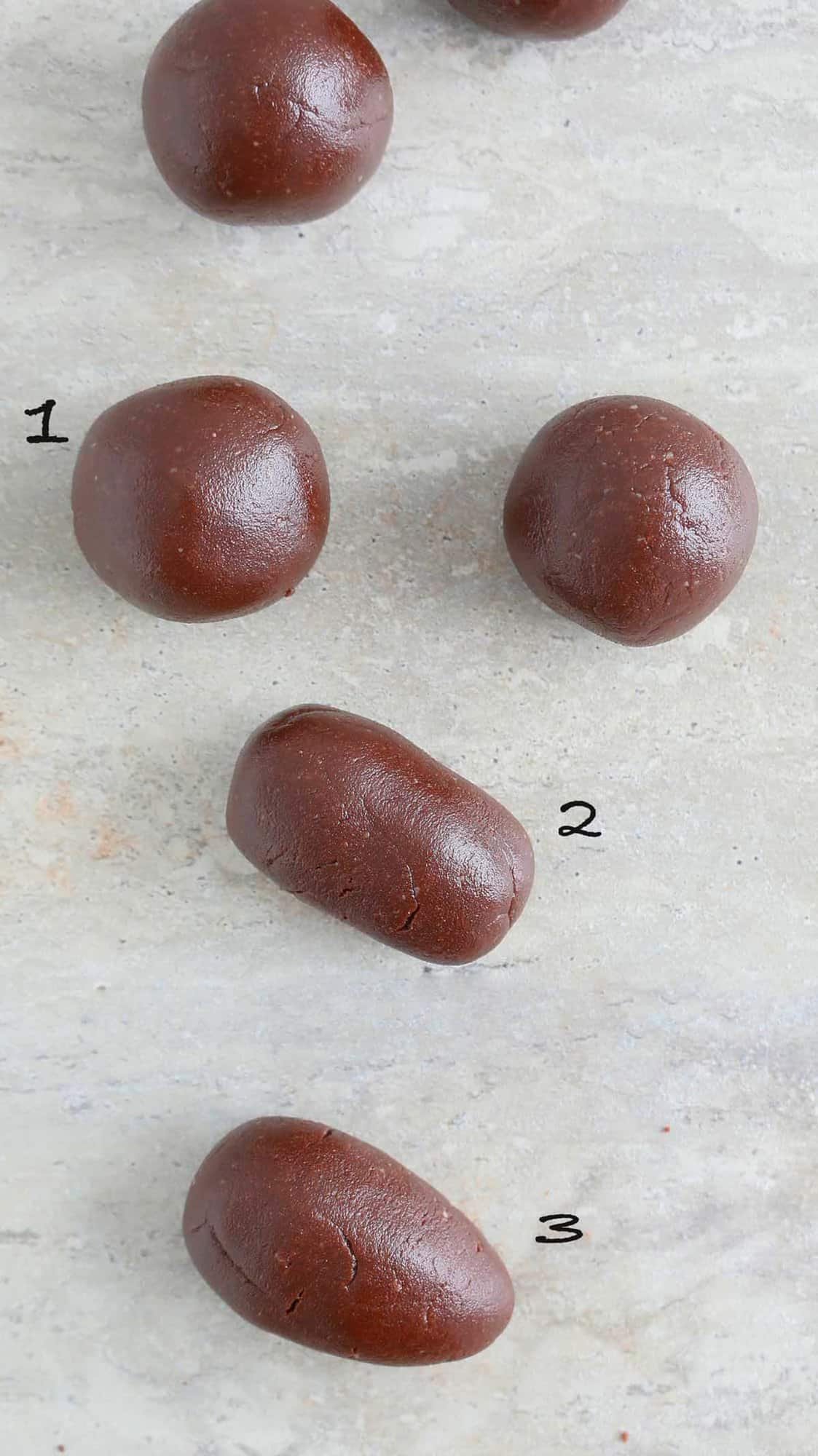 round and oblong pieces of chocolate dough on a grey board.