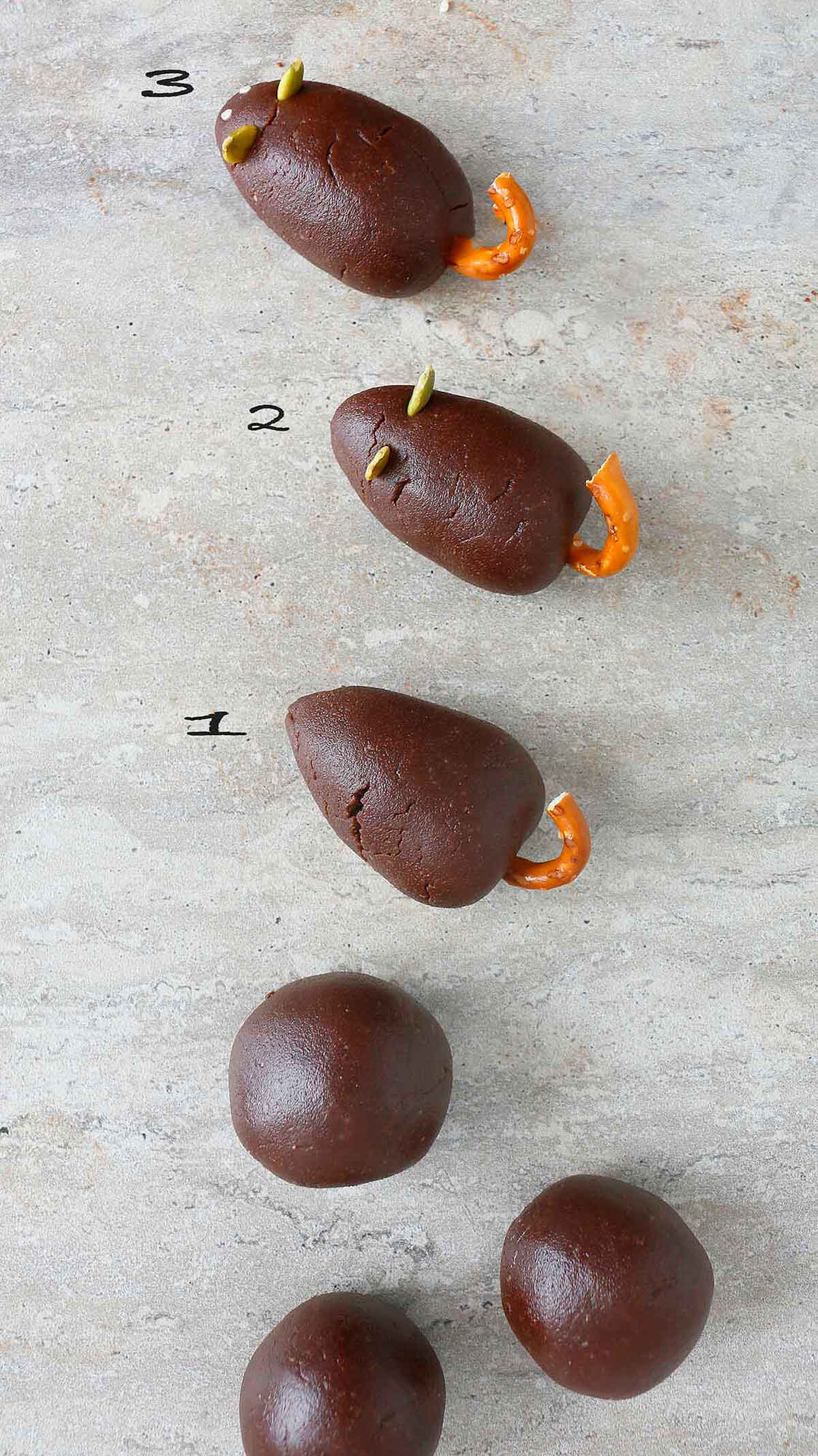 3 chocolate balls and shaped mice on a grey board.