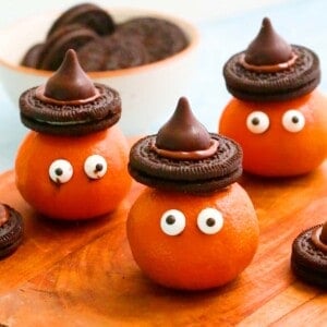 3 Halloween clementines with Oreo hats placed on a wooden board.