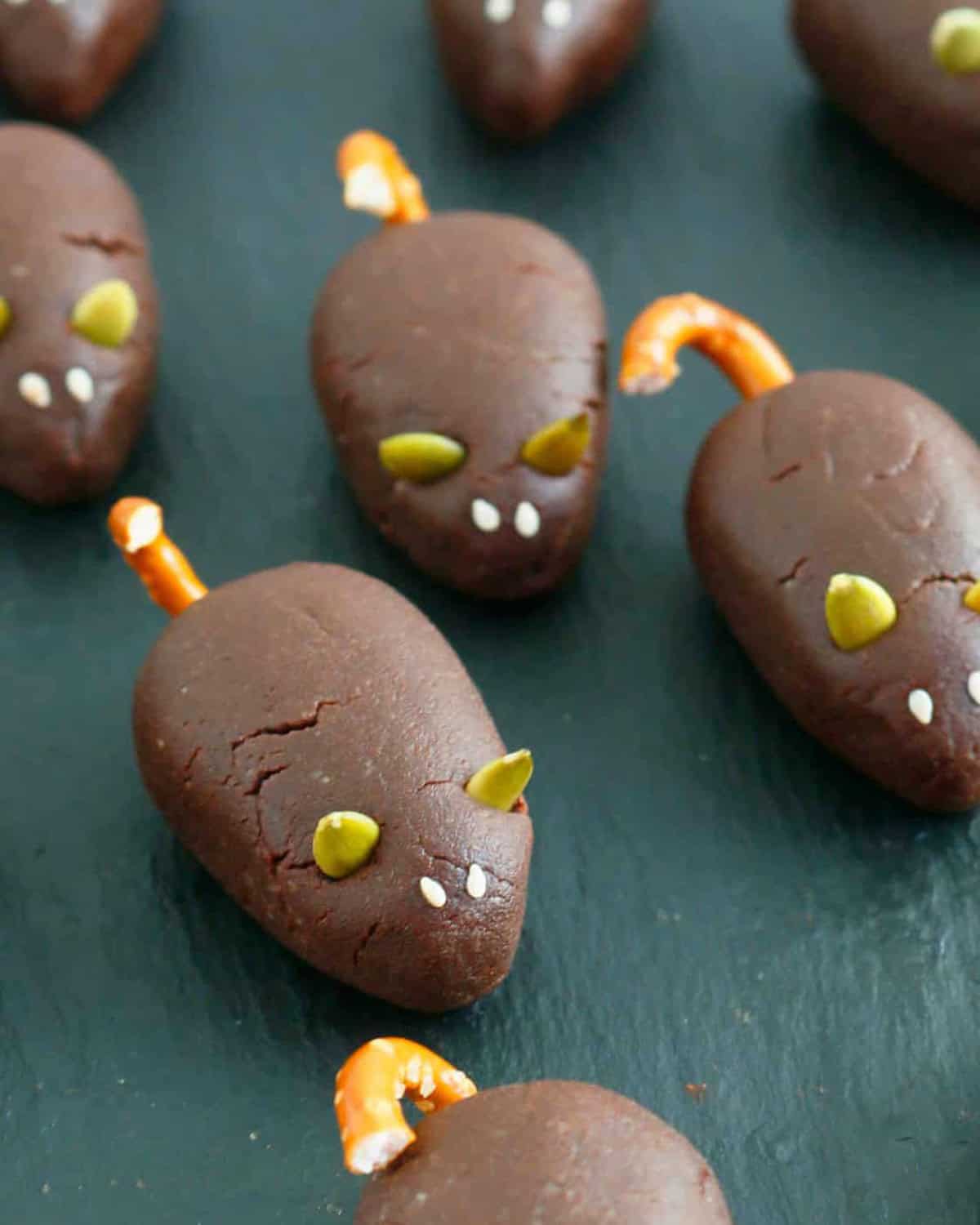 6 brown chocolate mice on a black board.