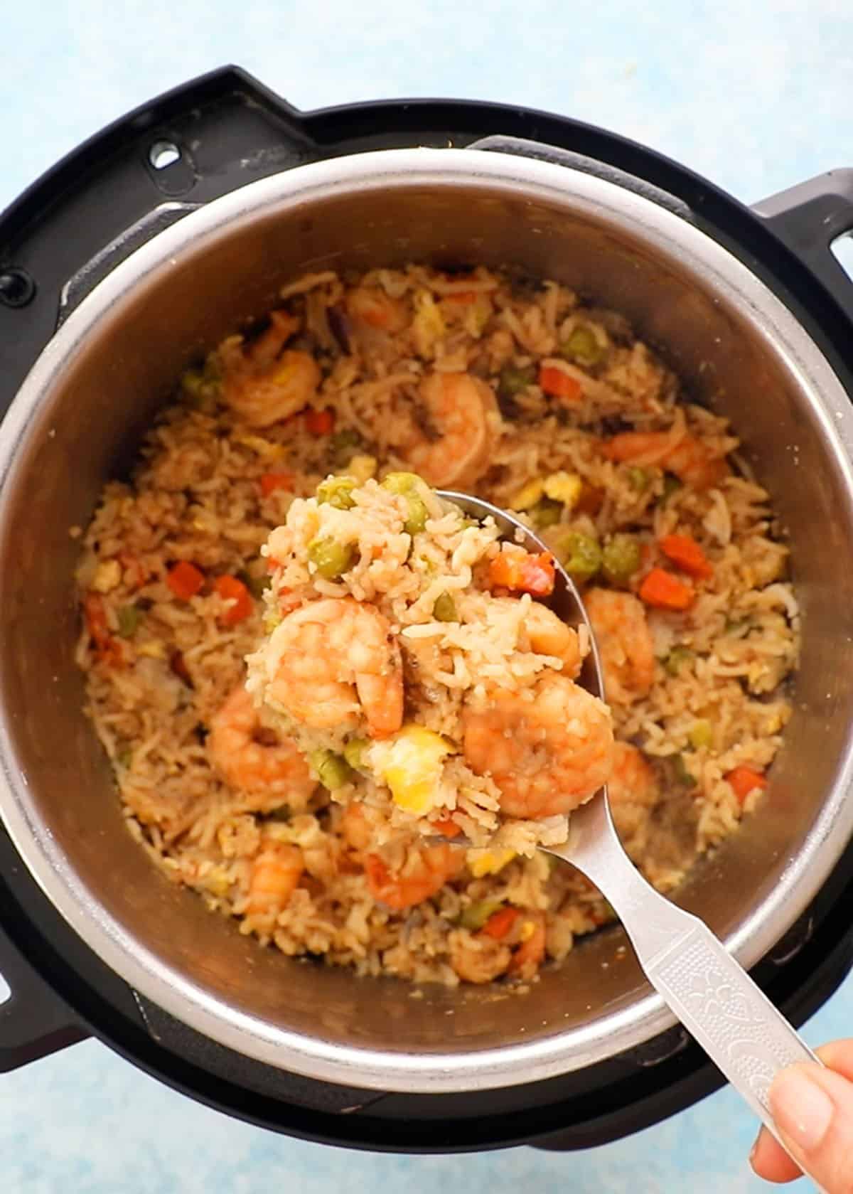 a spatula full of shrimp fried rice above an instant pot.