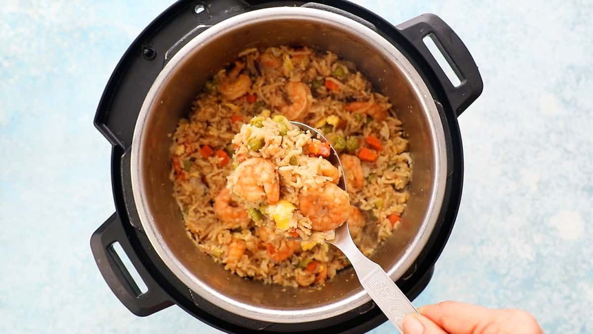 a spatula full of shrimp fried rice above an instant pot.