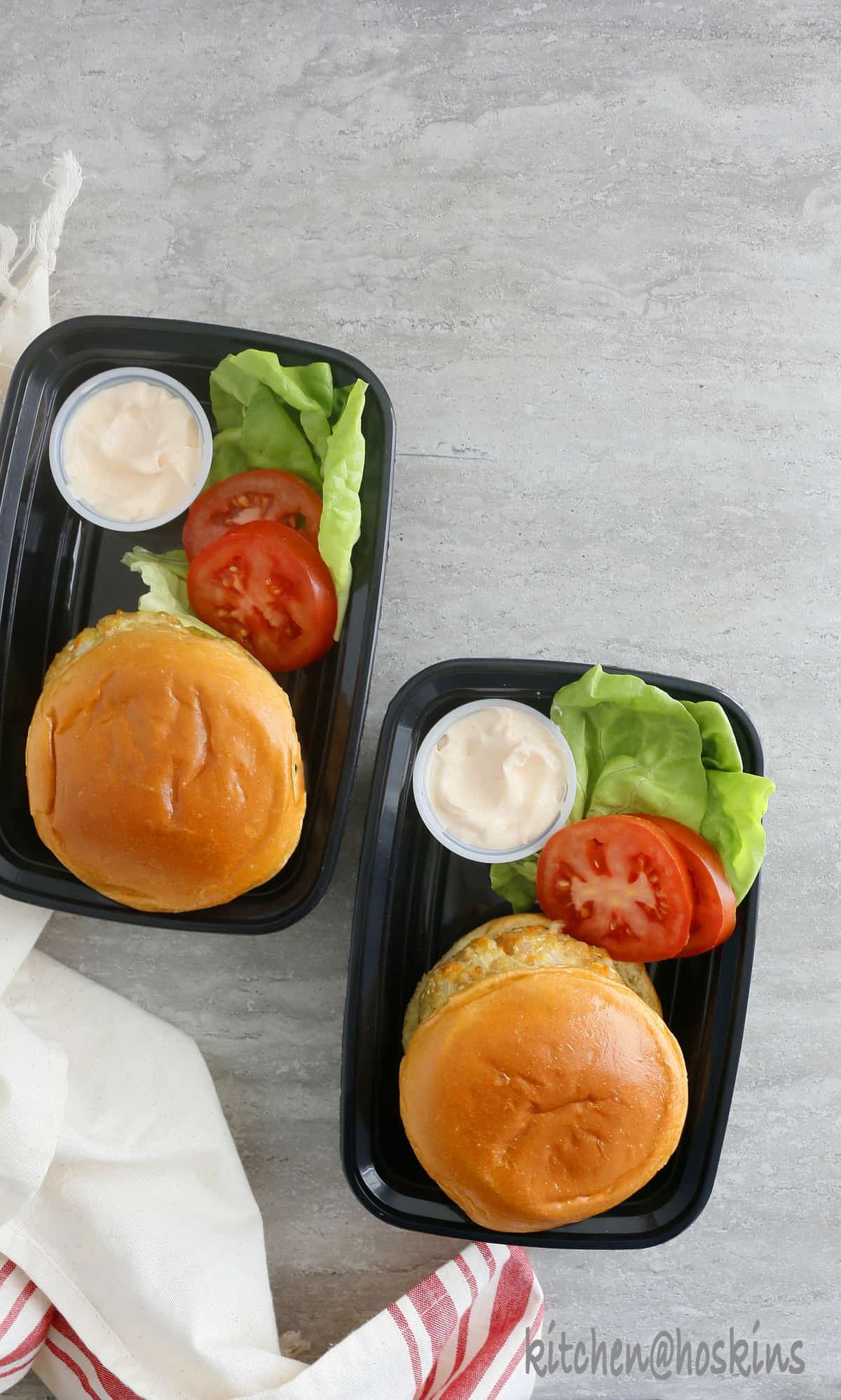Chicken burger packed in lunch boxes with sauce on the side in a seperate container