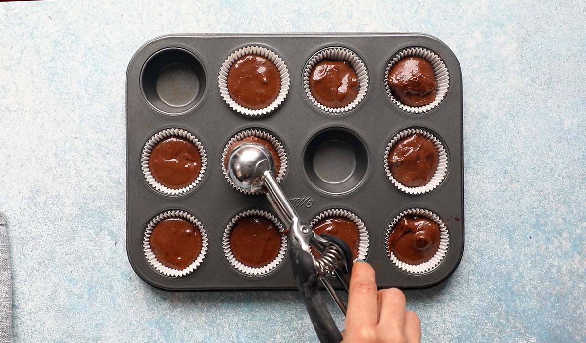 filling a muffin pan with brownie batter using a cookie scoop.