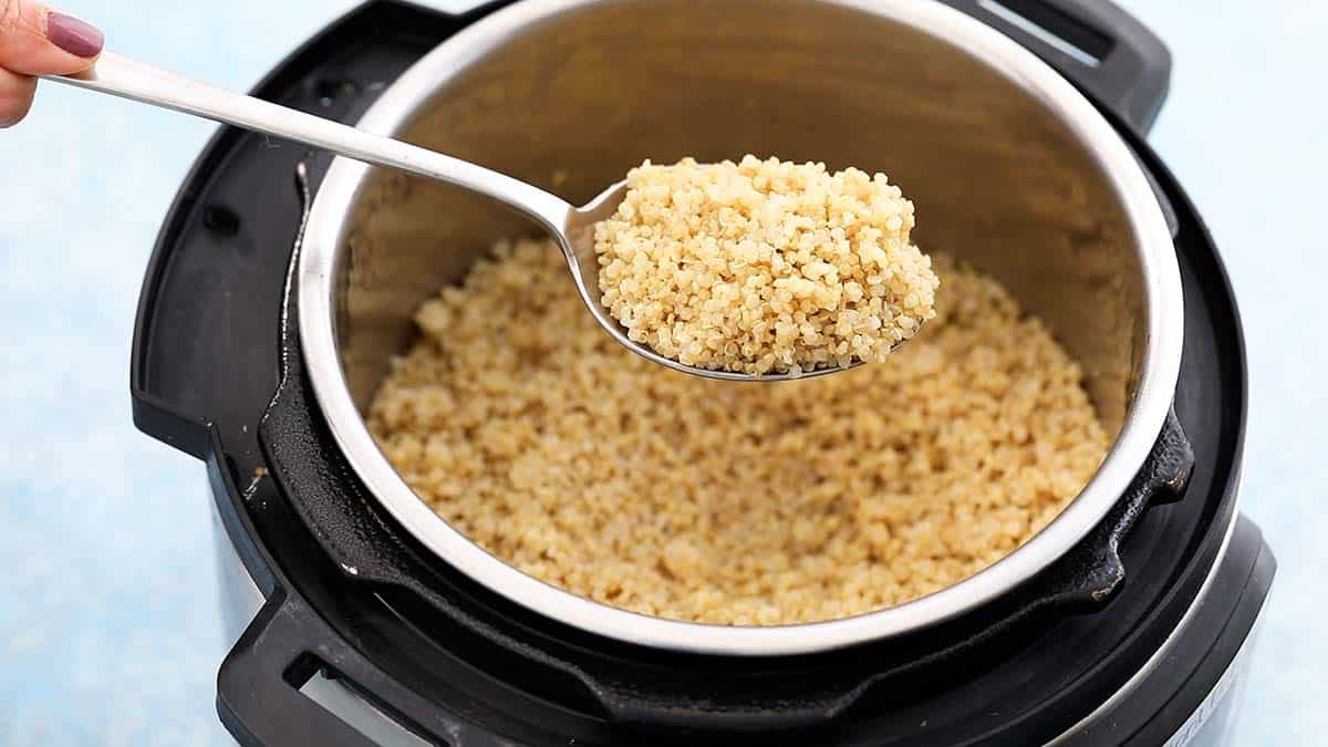 a spatula with cooked quinoa above an instant pot filled with the same.