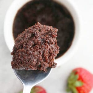 a spoonful of chocolate nutella cake placed above a white mug.