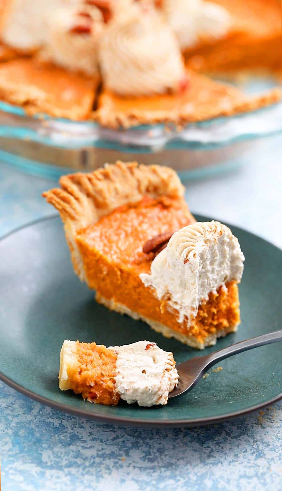 one slice of sweet potato pie on a green plate along with a fork filled with a bite.
