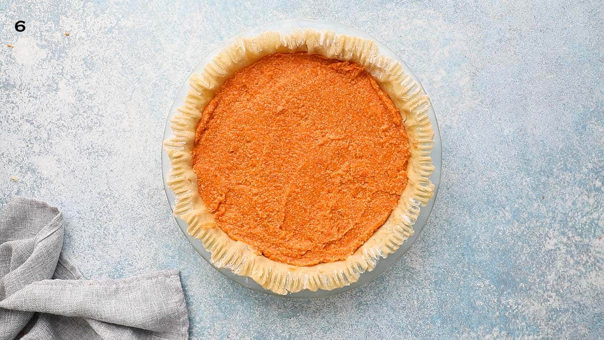 unbaked sweet potato pie shaped and filled in a glass dish.