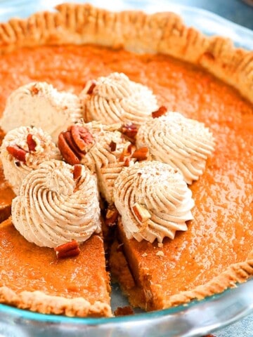 whipped cream topped sweet potato pie in a glass pie dish.