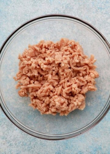 pink ground chicken in a large glass bowl.
