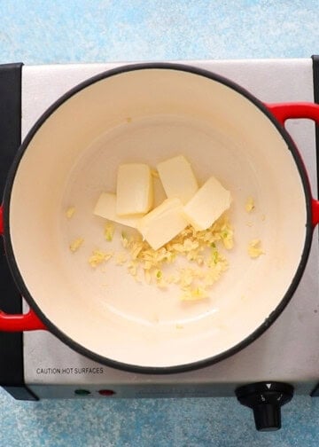 slices of white butter and chopped garlic in a white pot.