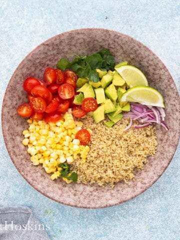 pink bowl with assembled quinoa salad ingredients.