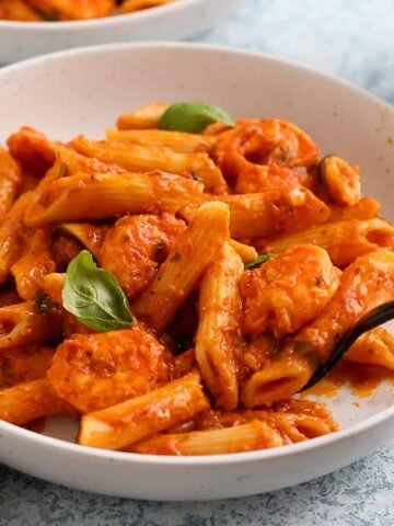 red shrimp pasta in a round white dish.