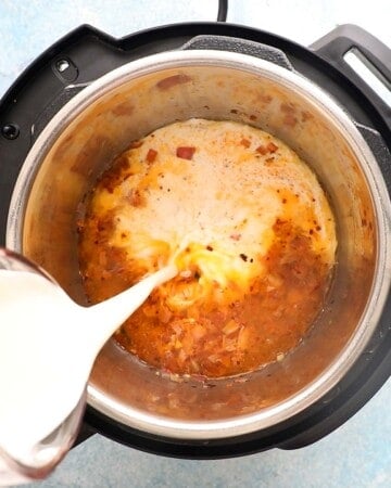 a hand pouring white cream into an instant pot.