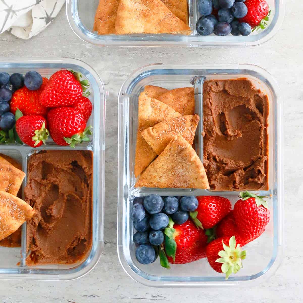 glass containers with sweet hummus, strawberries and pita chips.