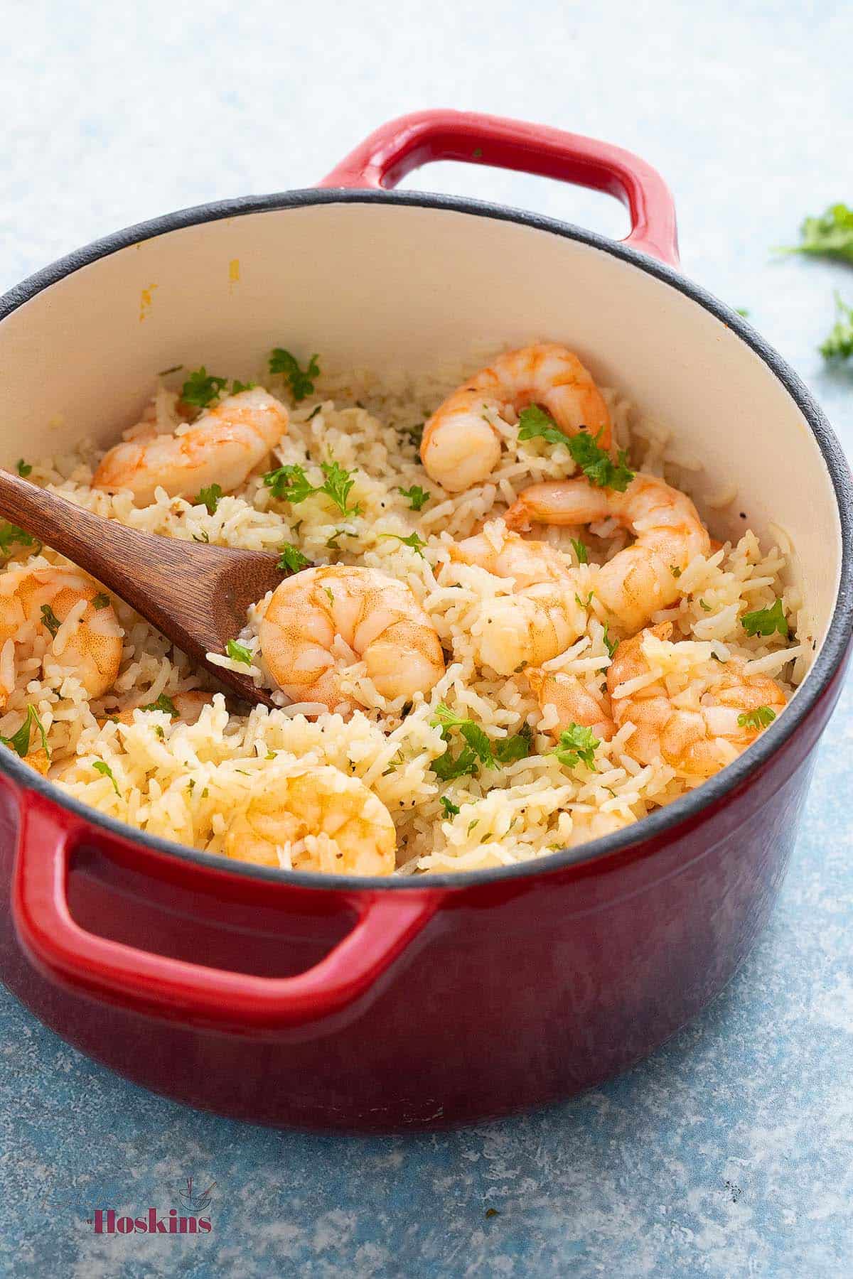 cooked rice and shrimp in a white pot with red handles.