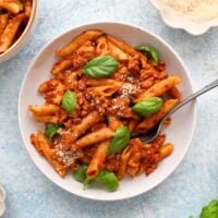 red penne pasta in two white bowls.