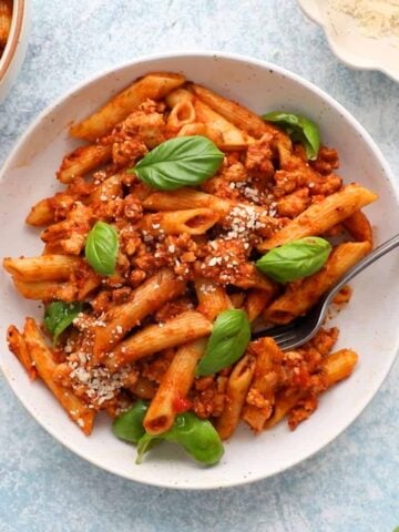 red penne pasta in two white bowls.