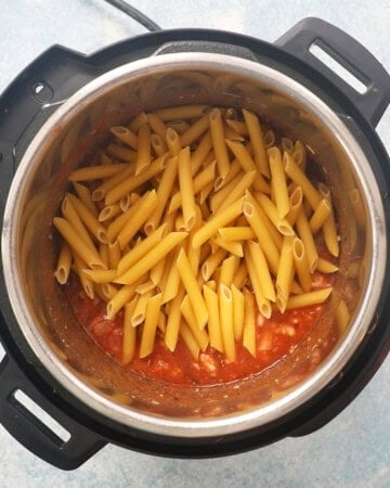 raw penne pasta along with red sauce in an instant pot.