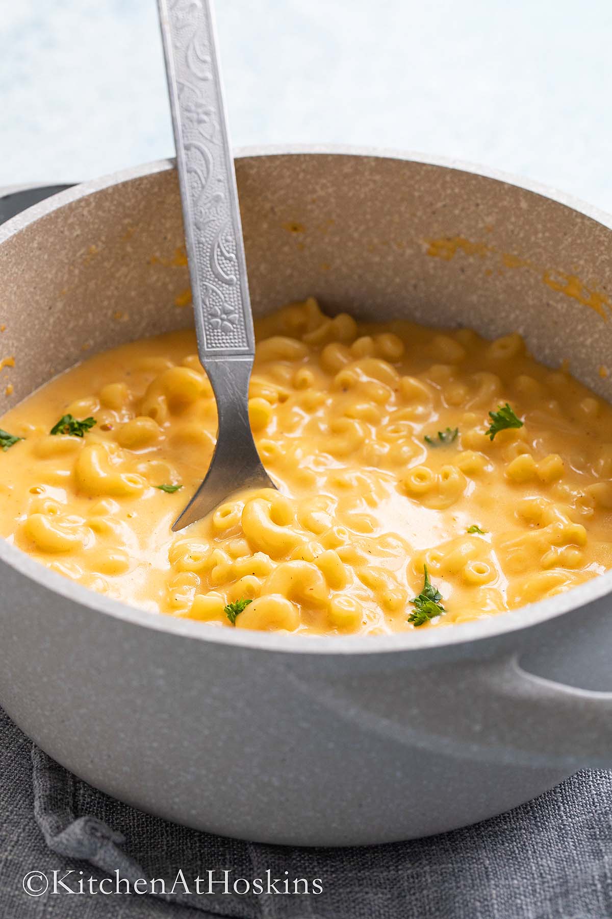 a pot with cooked mac and cheese along with a stainless steel spoon.