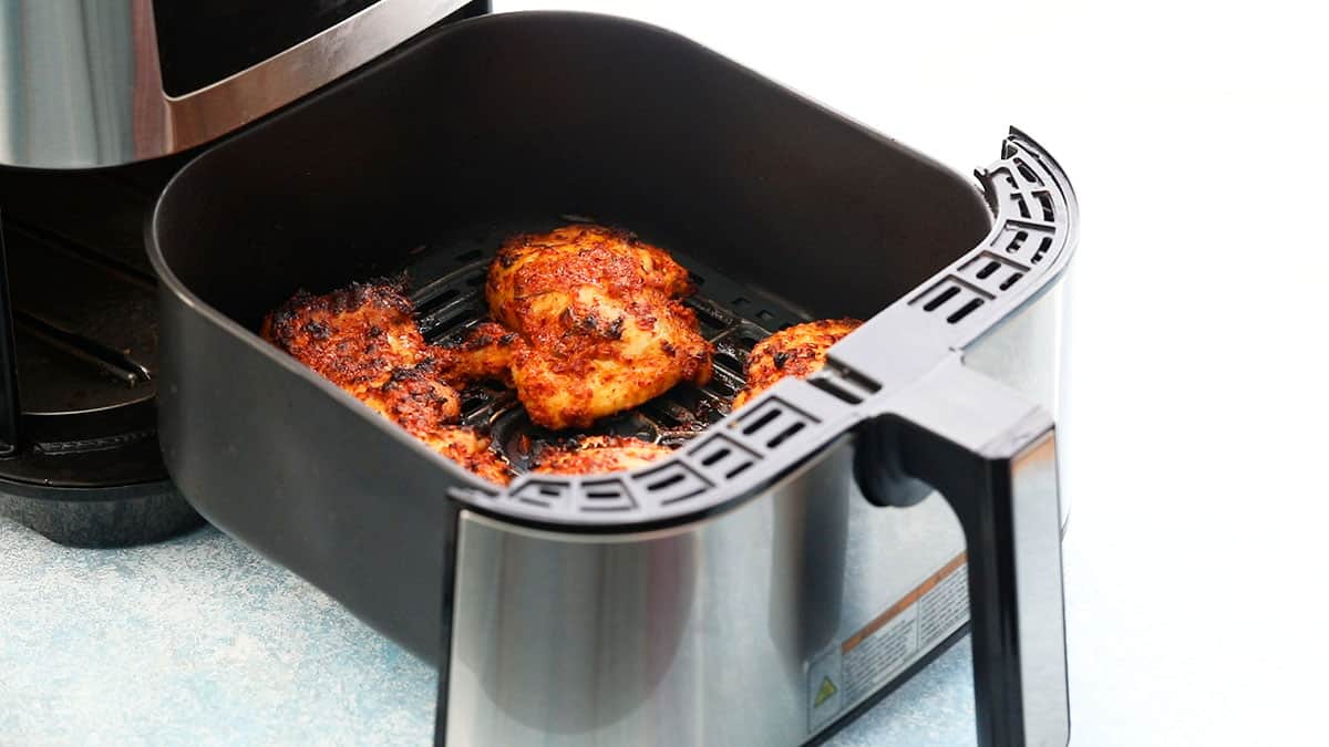 4 cooked chicken thighs in an air fryer.